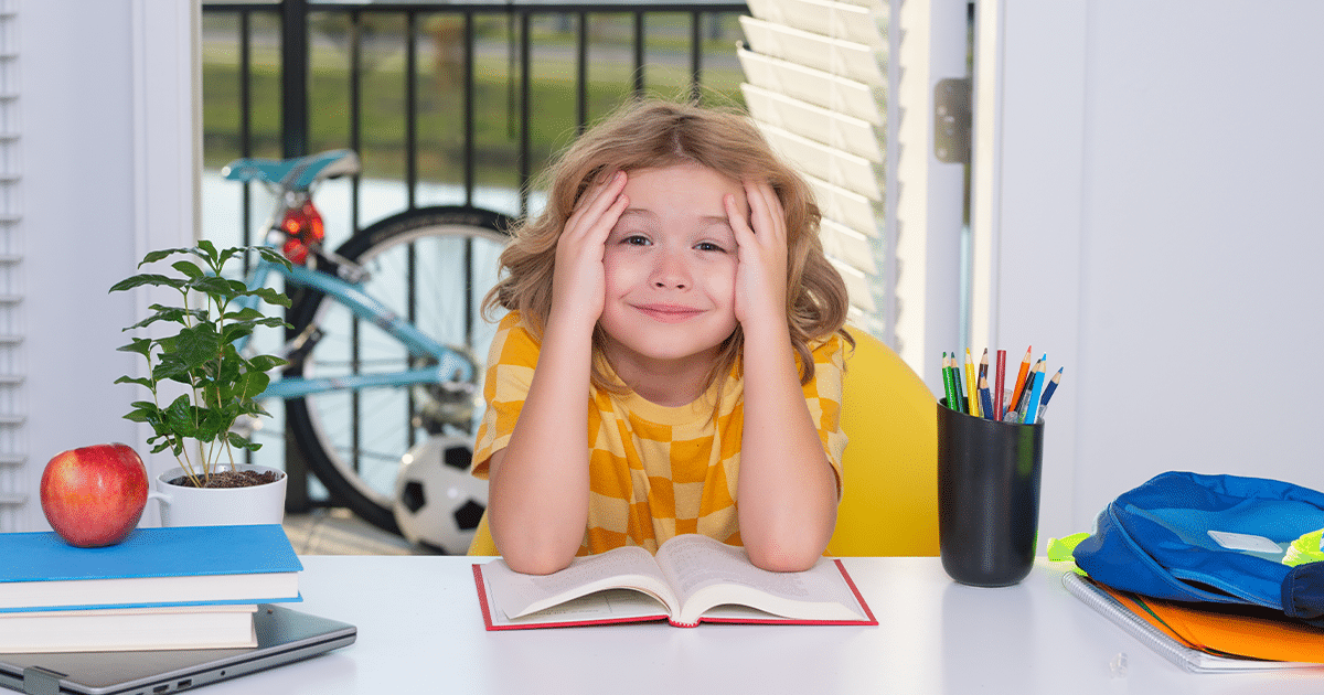 child sitting on a table with open book and hands in the face